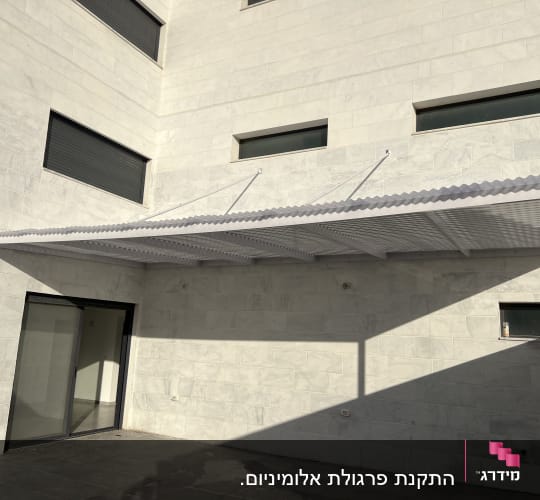 פרגולה מאלומיניום מחוברת לקיר חיצוני של בניין